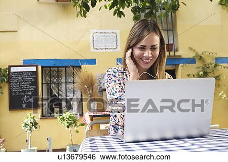 Stock Photograph - Young female tourist looking at laptop at sidewalk cafe, Valencia, Spain. Fotosearch