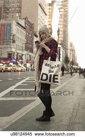 Stock Photography - Young female tourist texting on cellphone, New York City, USA. Fotosearch