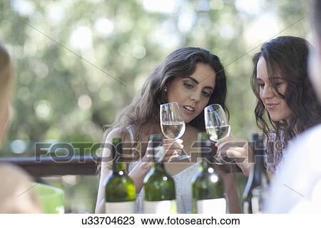Stock Image - Young friends tasting wine at vineyard bar. Fotosearch