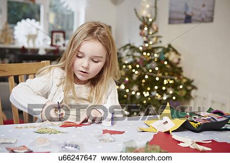 Stock Photo - Young girl cutting out paper preparing for christmas. Fotosearch
