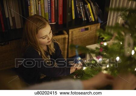 Young girl decorating christmas tree with baubles View Large Photo Image Stock Photography - Young girl decorating christmas tree with baubles. Fotosearch