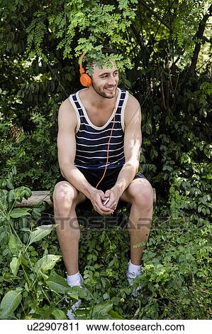 Young male runner taking a break in wooded park View Large Photo Image Stock Image - Young male runner taking a break in wooded park. Fotosearch