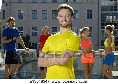 Young male trainer and class taking a break on city rooftop View Large Photo Image Stock Photo - Young male trainer and class taking a break on city rooftop. Fotosearch