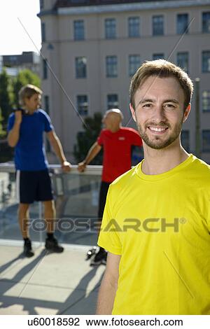 Young male trainer and male class taking a break on city rooftop View Large Photo Image Stock Image - Young male trainer and male class taking a break on city rooftop. Fotosearch