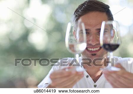 Young male waiter holding up glasses of red and white wines View Large Photo Image Stock Photo - Young male waiter holding up glasses of red and white wines. Fotosearch
