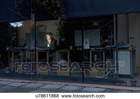 Stock Photo - Young man at home working late on computer. Fotosearch