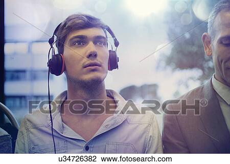 Young man daydreaming and listening to headphones on train View Large Photo Image Stock Image - Young man daydreaming and listening to headphones on train. Fotosearch