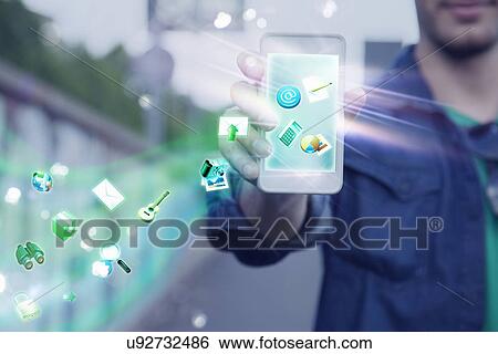 Stock Photograph - Young man holding up smartphone with apps and icons coming out of it. Fotosearch