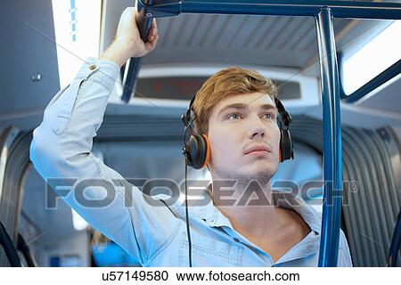 Young man in train carriage listening to headphones View Large Photo Image Stock Image - Young man in train carriage listening to headphones. Fotosearch