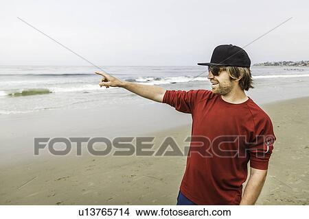 Picture - Young man pointing out to sea, Laguna Beach, California, USA. Fotosearch