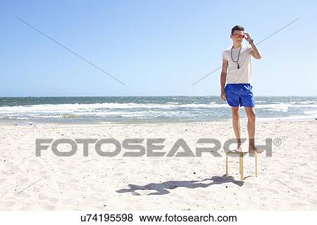 Young man posing on top of stool on beach, Port Melbourne, Melbourne, Australia View Large Photo Image Stock Photo - Young man posing on top of stool on beach, Port Melbourne, Melbourne, Australia. Fotosearch