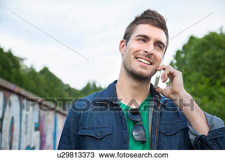 Young man talking on smartphone View Large Photo Image Stock Image - Young man talking on smartphone. Fotosearch