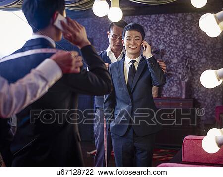Young man trying on suit in traditional tailors shop View Large Photo Image Stock Image - Young man trying on suit in traditional tailors shop. Fotosearch