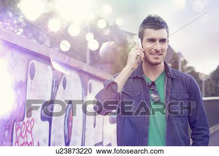 Young man using smartphone with glowing lights coming out of it View Large Photo Image Stock Image - Young man using smartphone with glowing lights coming out of it. Fotosearch