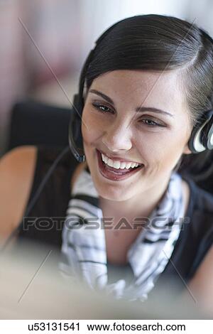 Young office worker chatting on headset View Large Photo Image Stock Image - Young office worker chatting on headset. Fotosearch
