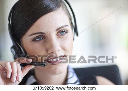 Young office worker talking on handset View Large Photo Image Stock Image - Young office worker talking on handset. Fotosearch