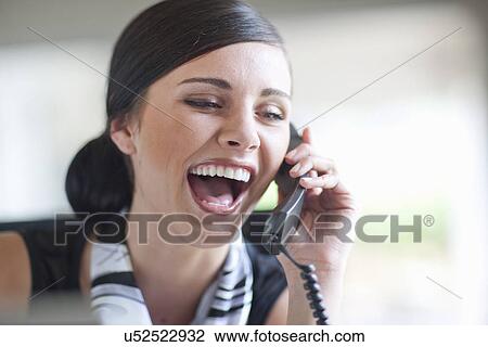 Stock Image - Young office worker talking on landline handset. Fotosearch