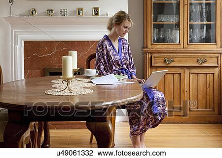 Young woman at home in dressing gown working on laptop View Large Photo Image Stock Image - Young woman at home in dressing gown working on laptop. Fotosearch