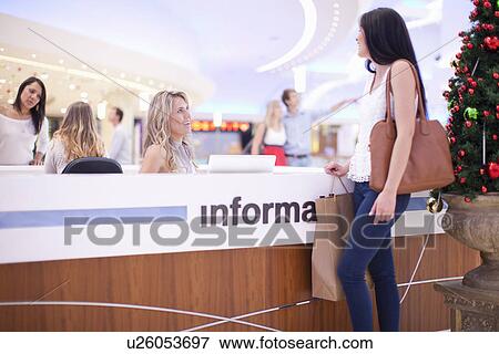 Stock Photo - Young woman at information desk in mall. Fotosearch