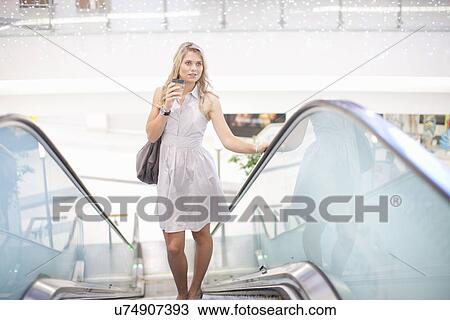 Young woman going up escalator in mall View Large Photo Image Stock Image - Young woman going up escalator in mall. Fotosearch