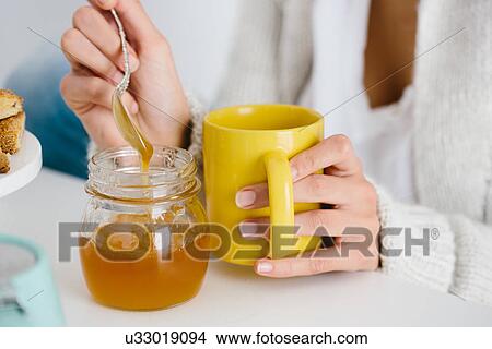 Picture - Young woman having honey drink. Fotosearch