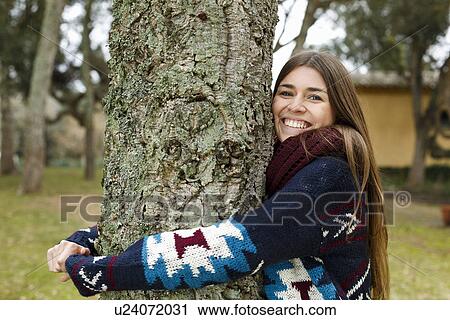 Stock Image - Young woman hugging tree in forest. Fotosearch