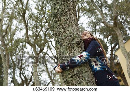 Young woman hugging tree in forest View Large Photo Image Stock Photo - Young woman hugging tree in forest. Fotosearch