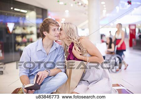 Young woman kissing man's cheek at mall View Large Photo Image Stock Image - Young woman kissing man's cheek at mall. Fotosearch
