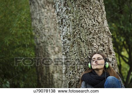 Stock Photo - Young woman listening to music in forest. Fotosearch