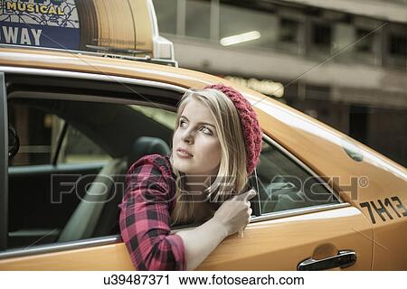 Stock Image - Young woman looking out from yellow cab, New York City, USA. Fotosearch