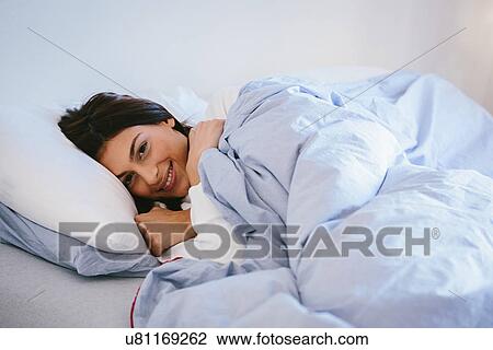 Young woman lying in bed View Large Photo Image Stock Image - Young woman lying in bed. Fotosearch