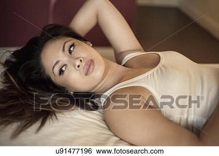 Young woman lying on bed looking sideways View Large Photo Image Stock Photograph - Young woman lying on bed looking sideways. Fotosearch