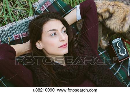 Young woman lying on blanket on grass View Large Photo Image Stock Image - Young woman lying on blanket on grass. Fotosearch