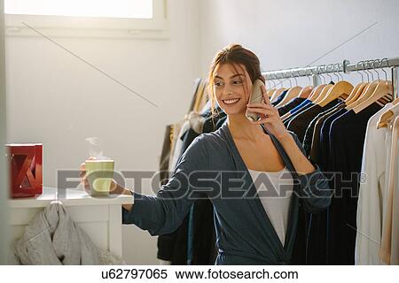 Young woman on phone getting ready to go out View Large Photo Image Stock Photography - Young woman on phone getting ready to go out. Fotosearch