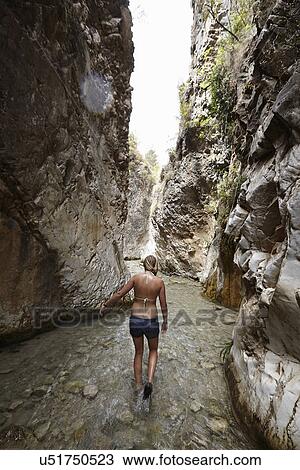 Stock Image - Young woman paddling in stream between rock formation, Costa del Sol, Spain. Fotosearch