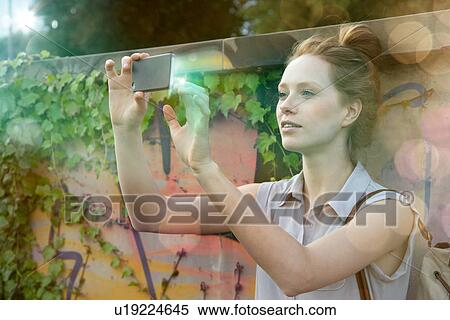 Young woman photographing self on illuminated smartphone View Large Photo Image Stock Photography - Young woman photographing self on illuminated smartphone. Fotosearch
