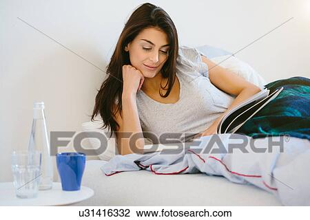Young woman reading in bed View Large Photo Image Stock Image - Young woman reading in bed. Fotosearch