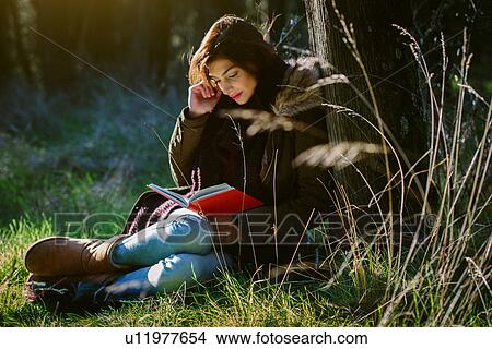 Picture - Young woman reading in the woods. Fotosearch