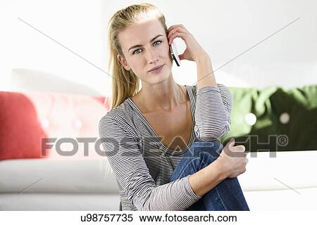 Stock Photography - Young woman sitting on floor, on phonecall. Fotosearch