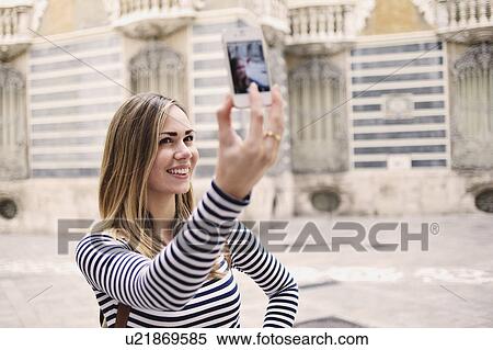 Stock Photography - Young woman taking self portrait outside Museum of Ceramics, Valencia, Spain. Fotosearch
