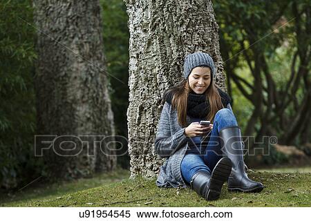 Stock Photography - Young woman using cellular phone in forest. Fotosearch