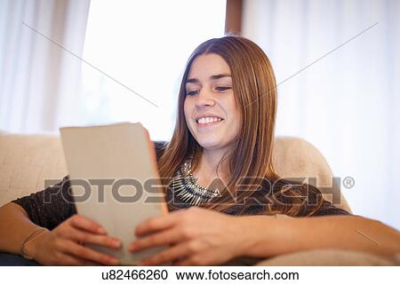 Young woman using digital tablet on sofa View Large Photo Image Stock Image - Young woman using digital tablet on sofa. Fotosearch