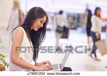 Young woman using laptop in mall View Large Photo Image Picture - Young woman using laptop in mall. Fotosearch