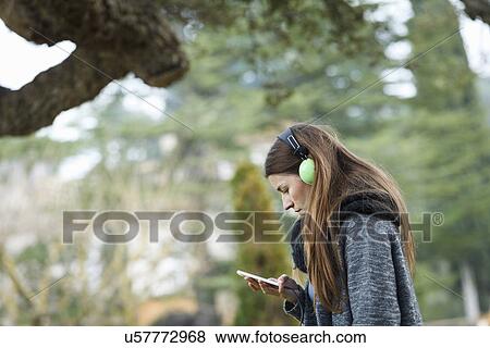 Stock Photo - Young woman using mp3 in forest. Fotosearch
