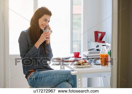 Young woman using telephone while breakfasting View Large Photo Image Stock Photo - Young woman using telephone while breakfasting. Fotosearch
