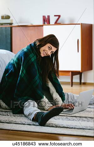 Young woman wearing blanket using laptop View Large Photo Image Stock Image - Young woman wearing blanket using laptop. Fotosearch