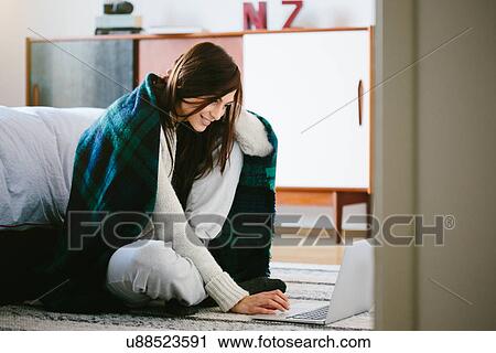 Young woman wearing blanket using laptop View Large Photo Image Stock Image - Young woman wearing blanket using laptop. Fotosearch