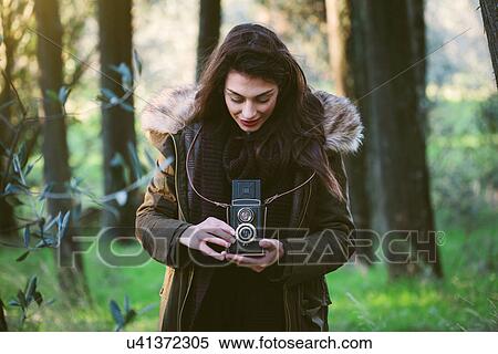 Stock Photography - Young woman with camera in the woods. Fotosearch