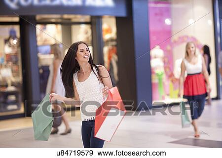 Stock Photo - Young women on shopping spree in mall. Fotosearch