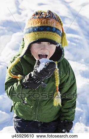 Stock Image - Boy (4-5) checking taste of snow. Fotosearch